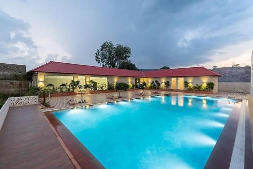 a large blue swimming pool in front of a building at Hotel Paandora Grand,Udaipur in Udaipur