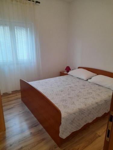 a bedroom with a large bed and two windows at Apartment Moonstone in Metajna