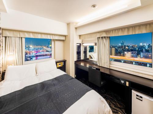 um quarto com uma cama e uma secretária com 2 janelas grandes em APA Hotel Asakusa Kuramae Kita em Tóquio