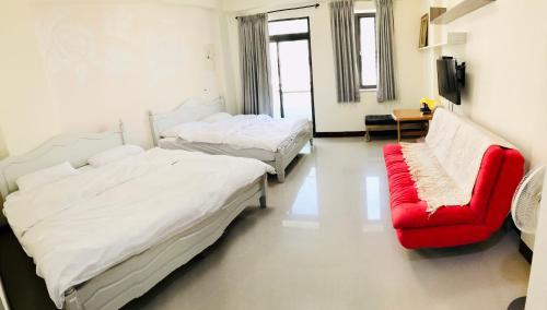 台南的住宿－花園夜市易民宿，一间设有两张床和一张红色沙发的房间