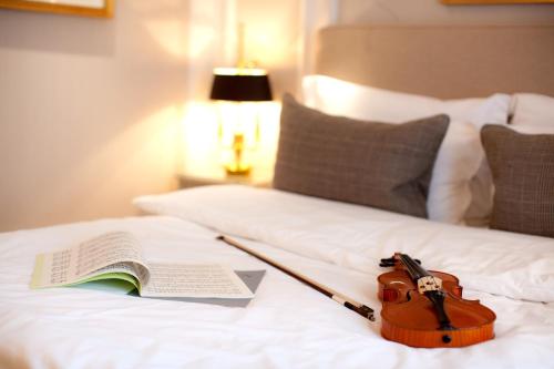 a violin and a book on a bed at Hotel München Palace in Munich