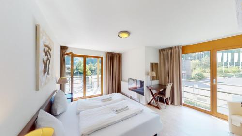 a white room with a bed and a desk at Walensee House & Apartments in Unterterzen