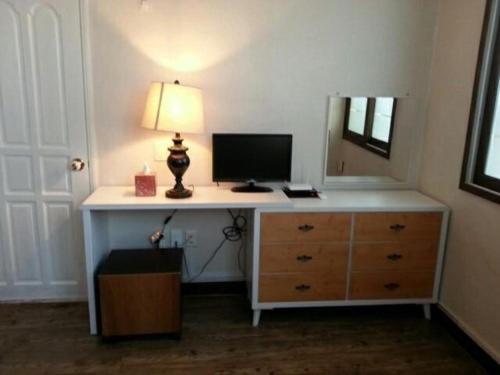 a room with a desk with a lamp and a dresser at Ramnant Guest House in Ulsan