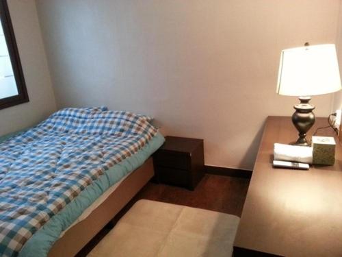 a bedroom with a bed and a table with a lamp at Ramnant Guest House in Ulsan