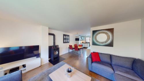 a living room with a blue couch and a tv at Walensee House & Apartments in Unterterzen