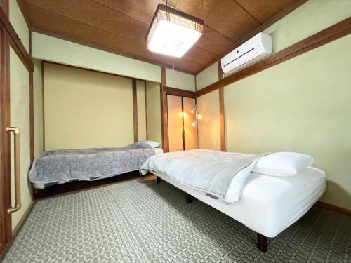 two beds in a room with two windows at 宿いちのみや in Ichinomiya