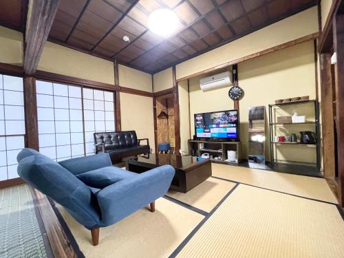 a living room with a blue chair and a tv at 宿いちのみや in Ichinomiya