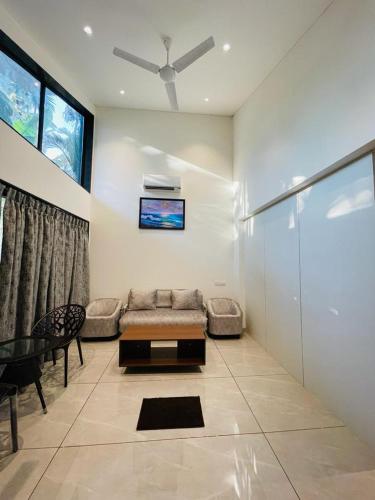 a living room with a couch and a ceiling fan at Coco Palms Resort, Diveagar in Diveagar