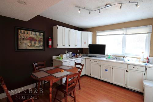 a kitchen with a table and a kitchen with white cabinets at Jenny Guest House in Yellowknife