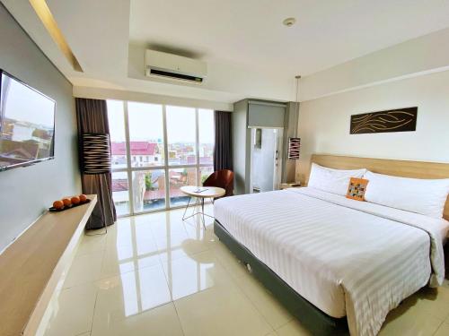 a bedroom with a large white bed and a balcony at Harper MT Haryono by ASTON in Jakarta