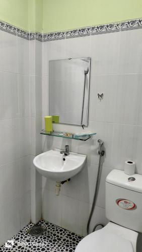 uma casa de banho com um lavatório, um WC e um espelho. em Nhà Nghỉ Lâm Tùng em Nha Trang