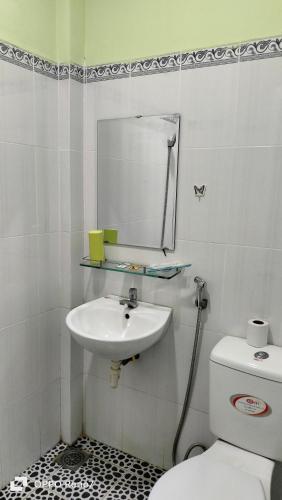 a bathroom with a sink and a toilet and a mirror at Nhà Nghỉ Lâm Tùng in Nha Trang
