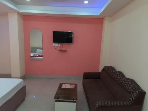 a living room with a couch and a tv on a wall at Hotel Geetanjali Palace in Kalyani
