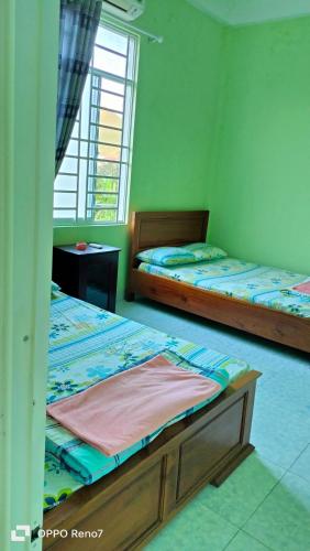 2 Betten in einem Zimmer mit grünen Wänden in der Unterkunft Nhà Nghỉ Lâm Tùng in Nha Trang