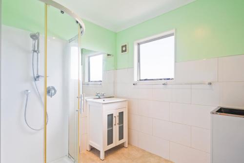 ein Bad mit einer Dusche und einem Waschbecken in der Unterkunft Bold Beauty - Paraparaumu Upstairs Holiday Unit in Paraparaumu