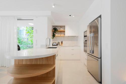 una cucina bianca con frigorifero in acciaio inossidabile di The Cove Noosa - Apartment 8 a Noosa Heads