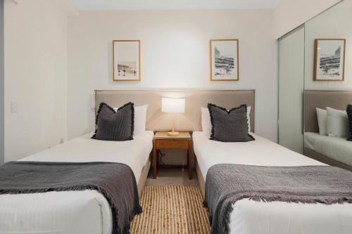 una camera d'albergo con due letti e una lampada di The Cove Noosa - Apartment 8 a Noosa Heads