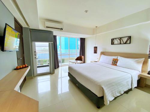 a bedroom with a large white bed and a television at Harper MT Haryono by ASTON in Jakarta