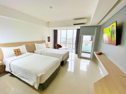 a hotel room with two beds and a television at Harper MT Haryono by ASTON in Jakarta