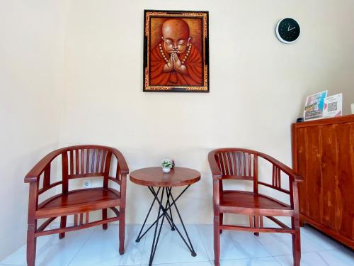 two chairs and a table with a picture on the wall at Andi Beach House in Canggu