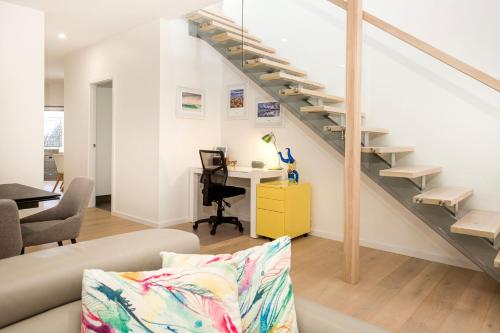 a living room with a couch and a staircase at Bowers Nest Pet Friendly 2 Mins Walk to Beach in Culburra Beach