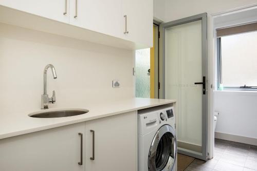 a white kitchen with a sink and a washing machine at Bowers Nest Pet Friendly 2 Mins Walk to Beach in Culburra Beach