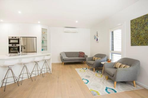 a living room with two chairs and a kitchen at Bowers Nest Pet Friendly 2 Mins Walk to Beach in Culburra Beach