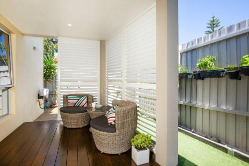 a patio with wicker chairs on a balcony at Bowers Nest Pet Friendly 2 Mins Walk to Beach in Culburra Beach