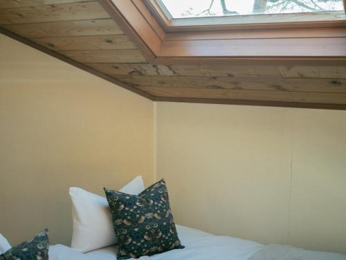 Zimmer mit einem Bett mit Kissen und einem Fenster in der Unterkunft Cottage Snowhills Hakuba in Hakuba
