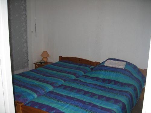 - une chambre dotée d'un lit avec des draps rayés bleus dans l'établissement Charmant T2 à Giens avec grande terrasse, piscine et à proximité des plages - FR-1-335-160, à Hyères