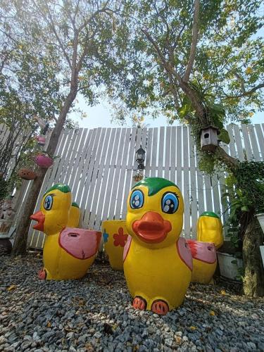 three rubber ducks sitting on the ground in front of a fence at Saan Rak Resort in Prachuap Khiri Khan