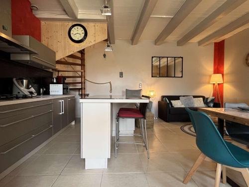 d'une cuisine et d'un salon avec une table et une horloge. dans l'établissement Maison calme avec terrasse à Saint-Denis-d'Oléron - 5 pers, proche plage et piste cyclable - FR-1-246A-205, à Saint-Denis-dʼOléron