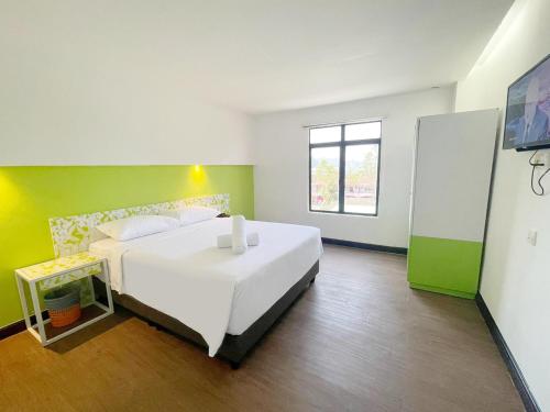 1 dormitorio con cama blanca y pared verde en Citin Langkawi by Compass Hospitality, en Kuah