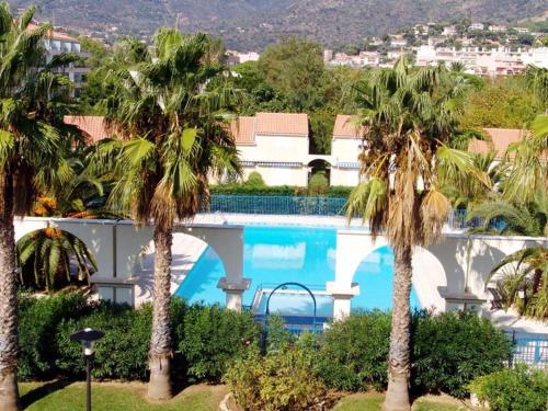 un complexe avec piscine et palmiers dans l'établissement Studio cabine avec piscine, parking privé et terrasse - 4 couchages, Le Lavandou - FR-1-251-478, au Lavandou