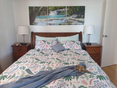 een bed in een slaapkamer met 2 lampen en een schilderij bij A Little Piece of Paradise in Yeppoon