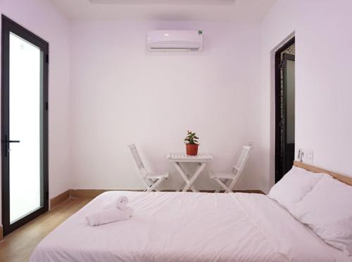 um quarto com uma cama branca, uma mesa e cadeiras em Chàm’s Corner Lookout Homestay & Restaurant em Tân Hiệp