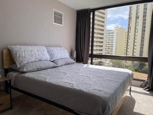 1 dormitorio con cama y ventana grande en Waikiki Sunset en Honolulu