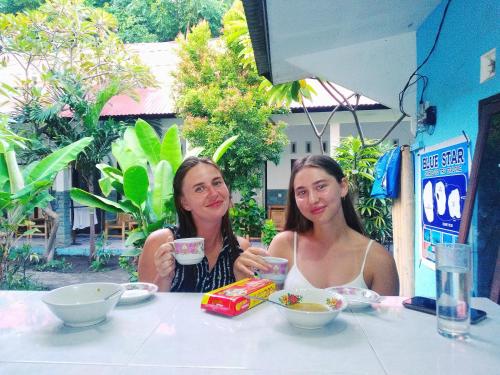 Deux femmes assises à une table avec des boissons dans l'établissement Ping Pong homestay Gili Trawangan, à Gili Trawangan