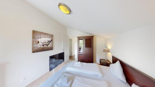 a bedroom with a large white bed and a tv at Walensee House & Apartments in Unterterzen