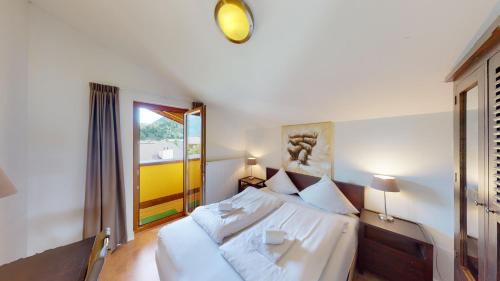 a bedroom with a white bed and a window at Walensee House & Apartments in Unterterzen