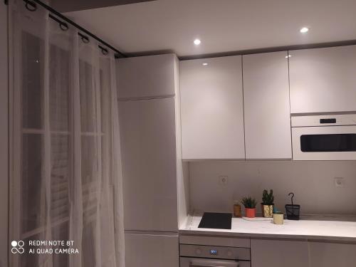 une cuisine avec des armoires blanches et un comptoir dans l'établissement Appartement moderne au centre de Paris, à Paris