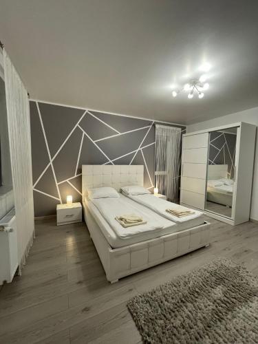 a bedroom with a large white bed and a mirror at Merci Apartament 1,0 in Sibiu