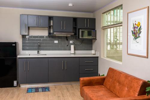 a kitchen with black cabinets and a brown couch at Hotel Otoya 1907 Downtown in San José
