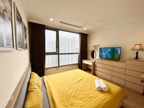 a bedroom with a yellow bed and a television at BOM HOMES- VINHOMES TIMES CITY- 2BR-LUXURY APt in Hanoi