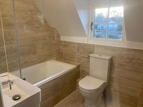a bathroom with a toilet and a tub and a sink at Laurel Cottage in Weymouth