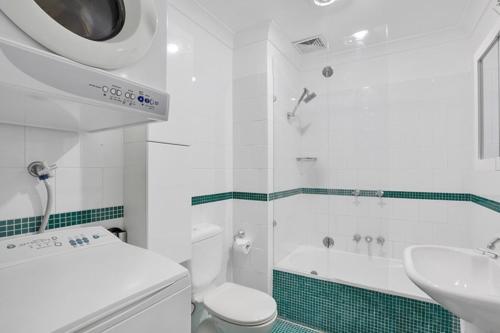 Un baño blanco con inodoro y lavabo. en Ultimate 2-Bed Apartment in Surry Hills - Ultimate Convenience, en Sídney