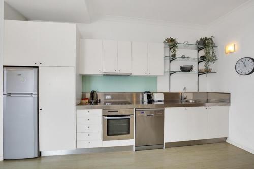 a kitchen with white cabinets and stainless steel appliances at Ultimate 2-Bed Apartment in Surry Hills - Ultimate Convenience in Sydney
