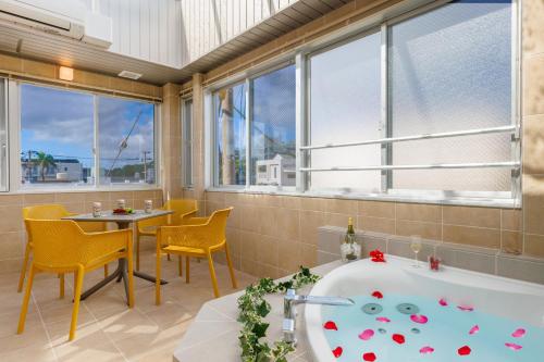 uma casa de banho com uma banheira, uma mesa e cadeiras em Southerlies Condominium Onna em Onna