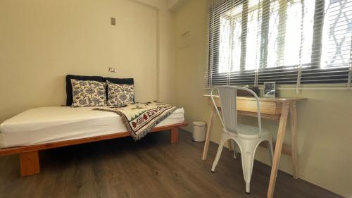 a bedroom with a bed and a table and a chair at Cozy House Hostel in Hualien City