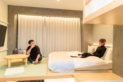 two people sitting on a bed in a bedroom at Sakura Cross Hotel Ueno Iriya Annex in Tokyo